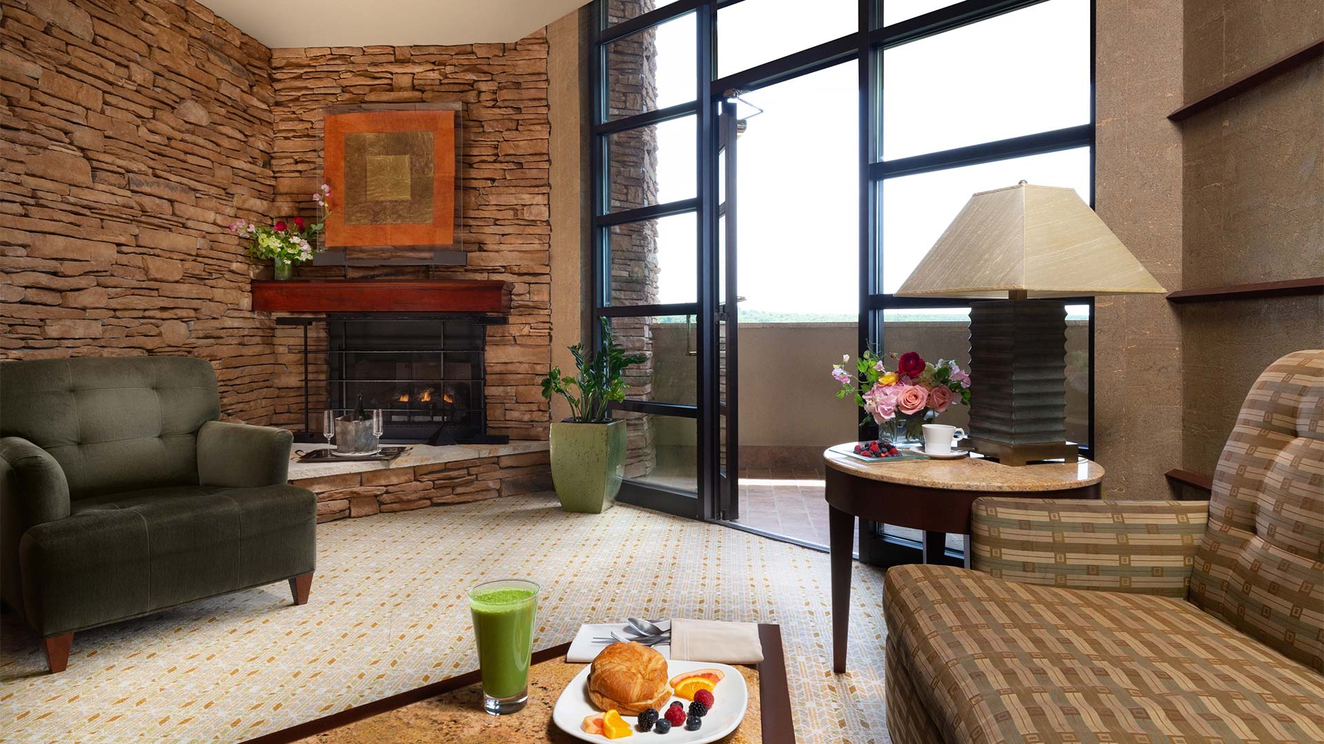 interior shot of Falling Rock's double suite living area. There is a couch and an arm chair around a coffee table with breakfast on it. There is a fireplace in the background and a door leading out onto a balcony