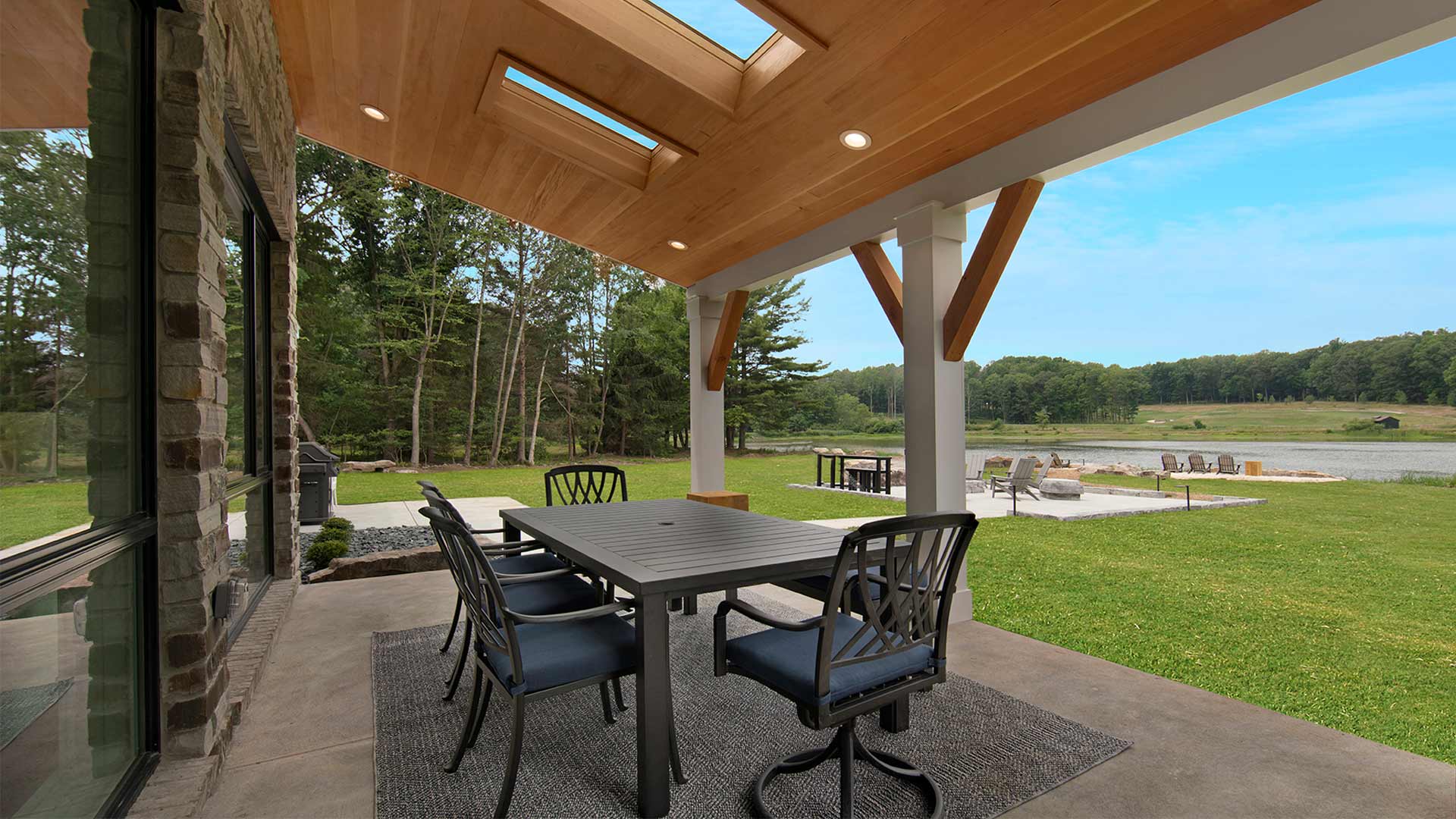 exterior shot of the patio with a table and chairs. There is a covering over the patio and a view of the lake