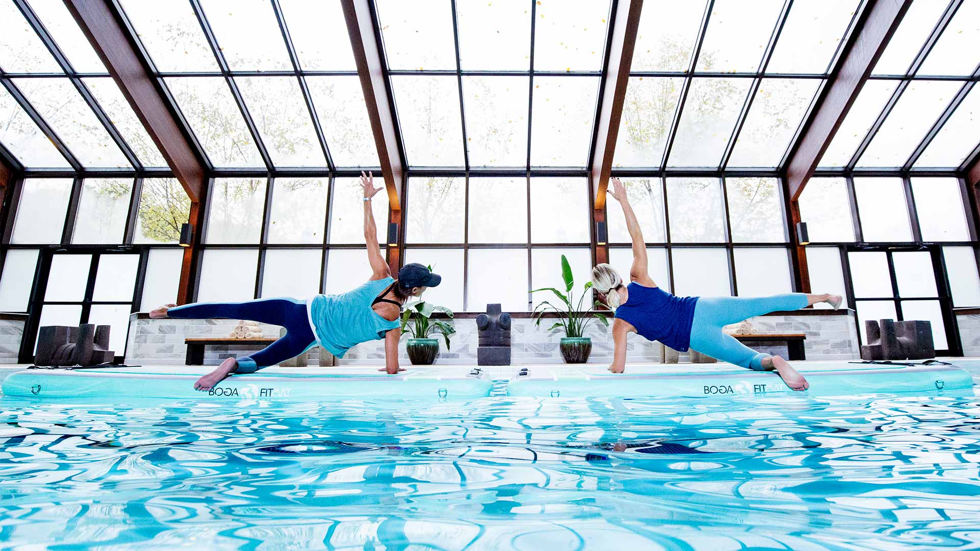 two people is blue workout gear are doing side planks at the edge of a pool