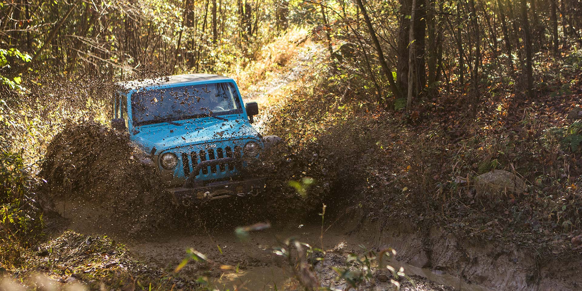 blue jeep driving into mud