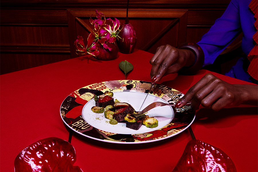 woman cutting food on a red table in a red room with red flowers