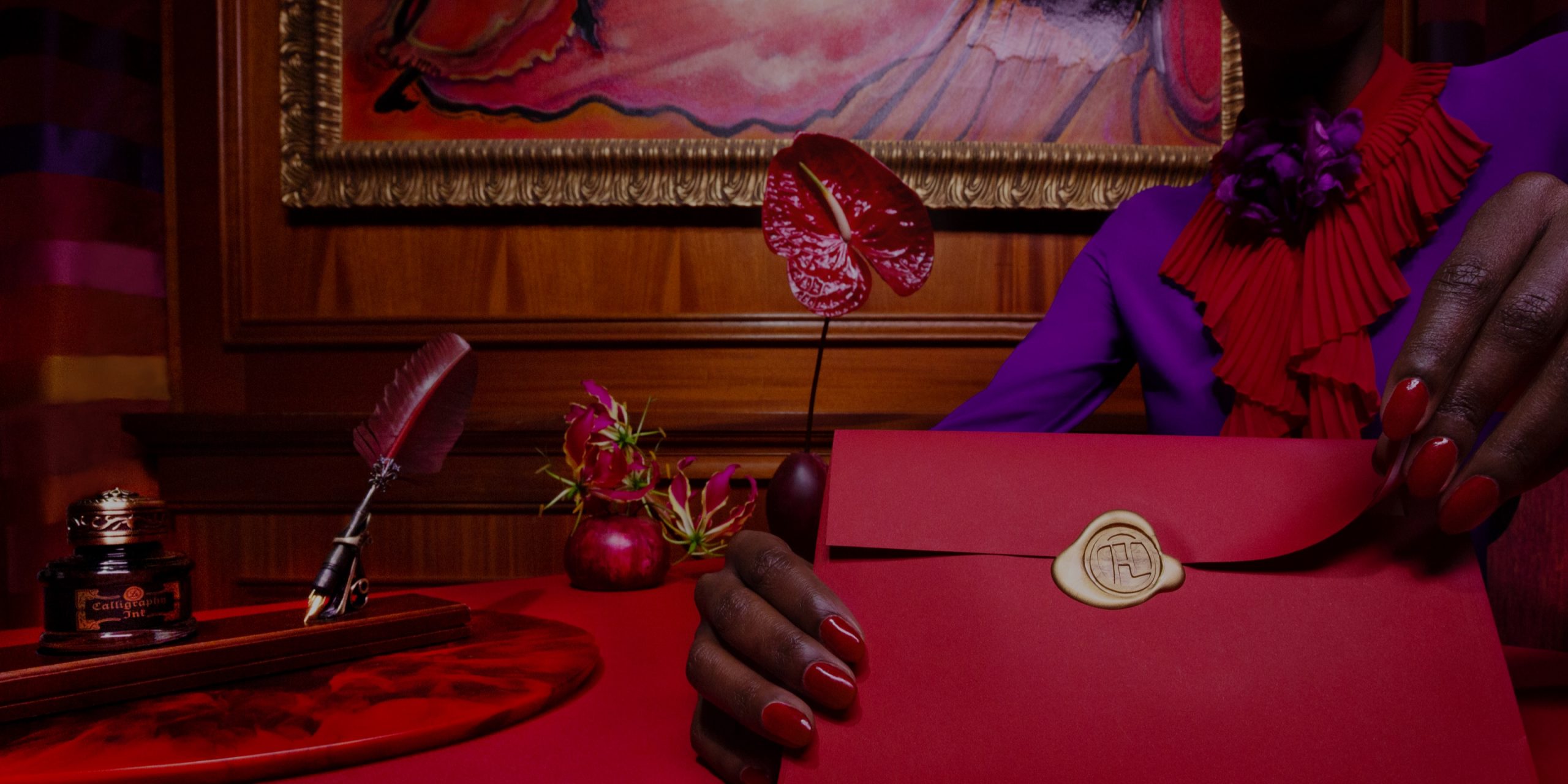 a close up shot of a woman in a purple blouse and bright red nails opening a red envelope.