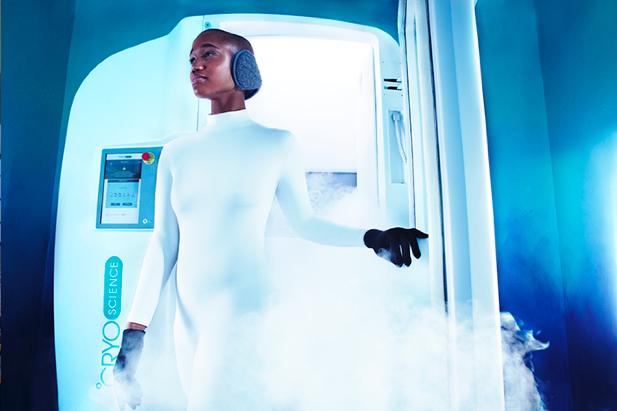 a woman in a futuristic white jumpsuit is walking out of a steam chamber
