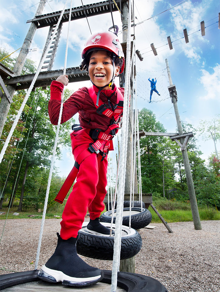 little boy playing on low ropes course