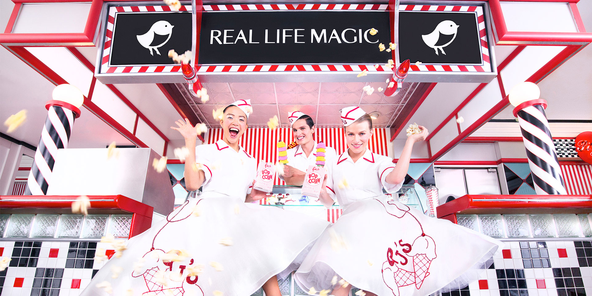 "Real Life Magic" sign above three girls in big skirts and hats serving ice cream