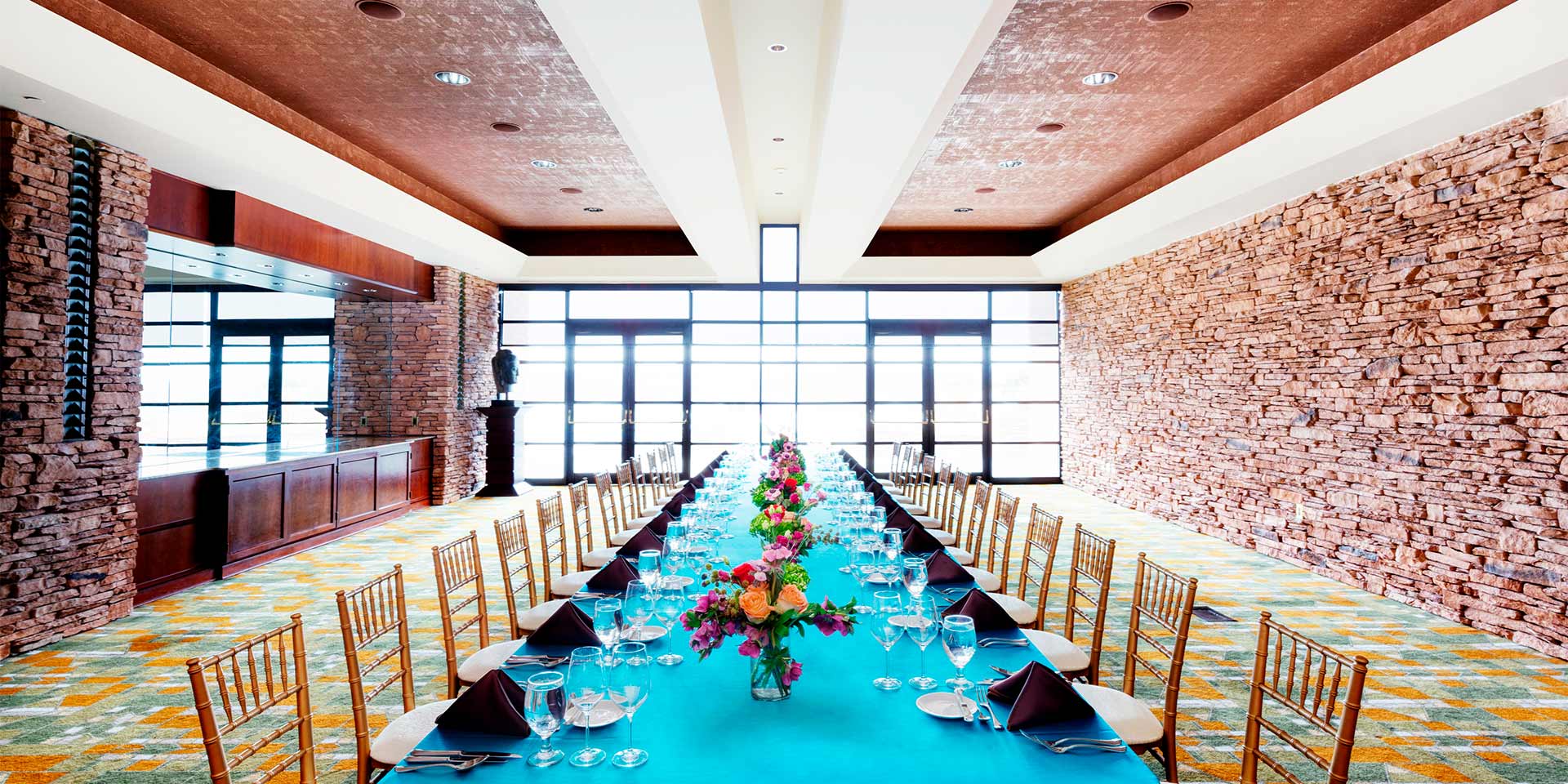 large dining table with blue table cloth and large windows