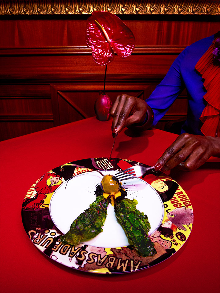 picture of someone cutting food on a patterned plate on a red table