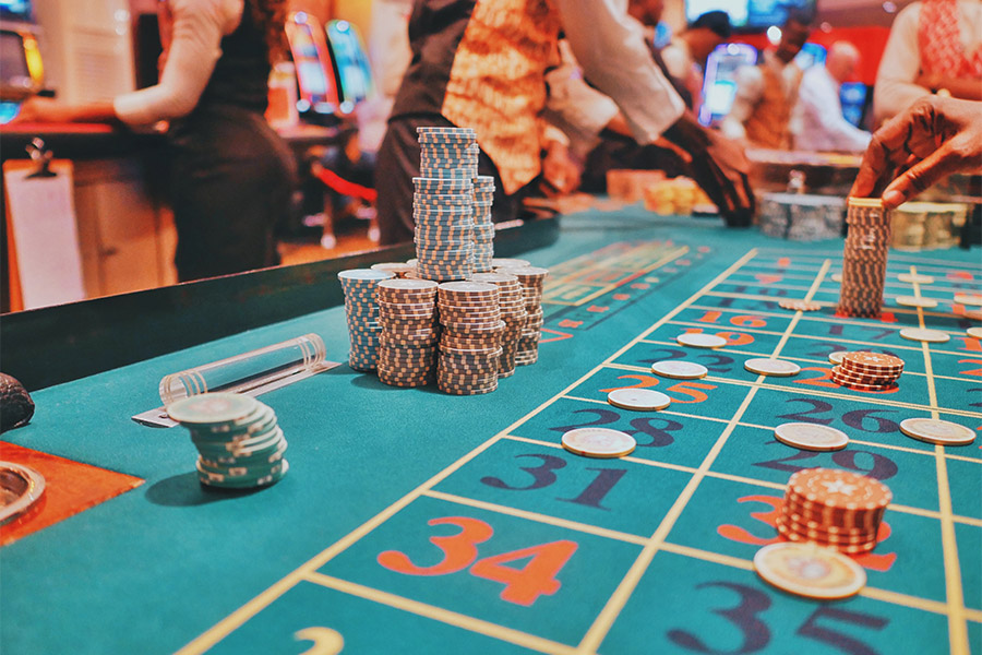 A bustling poker table decorated with red and green poker chips scattered around and stacked.