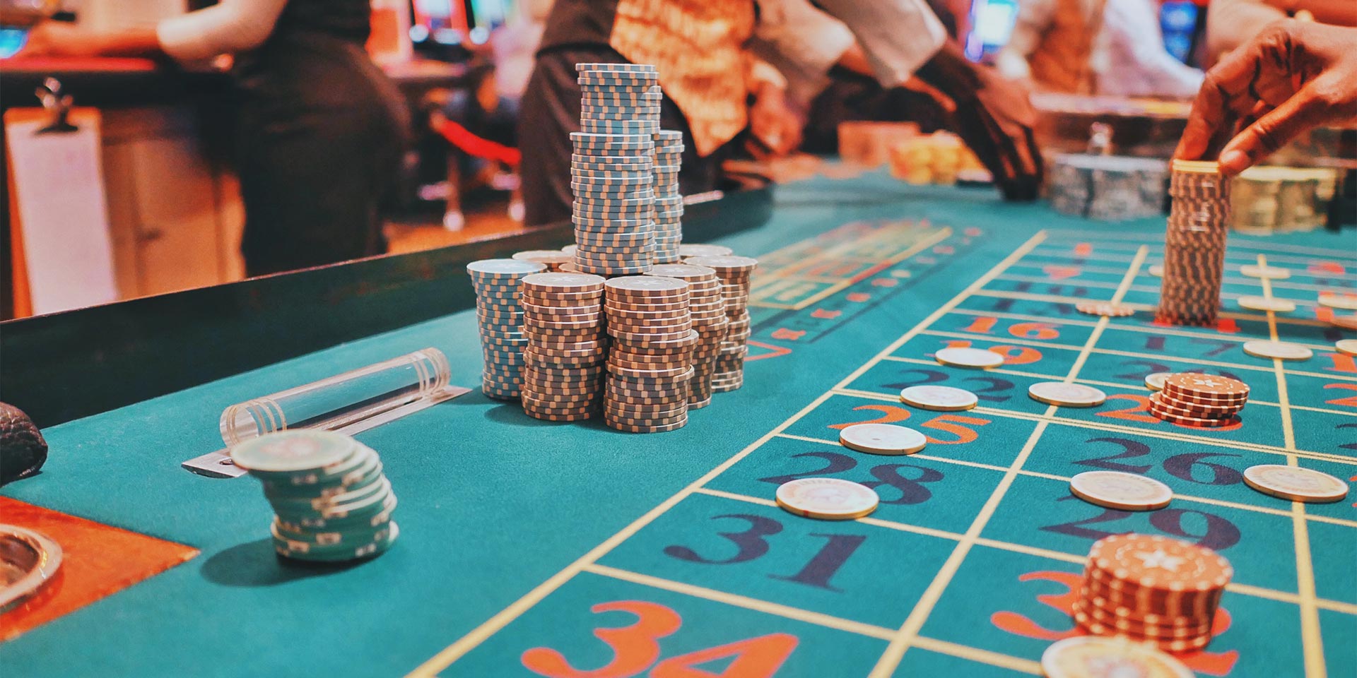 A bustling poker table decorated with red and green poker chips scattered around and stacked.