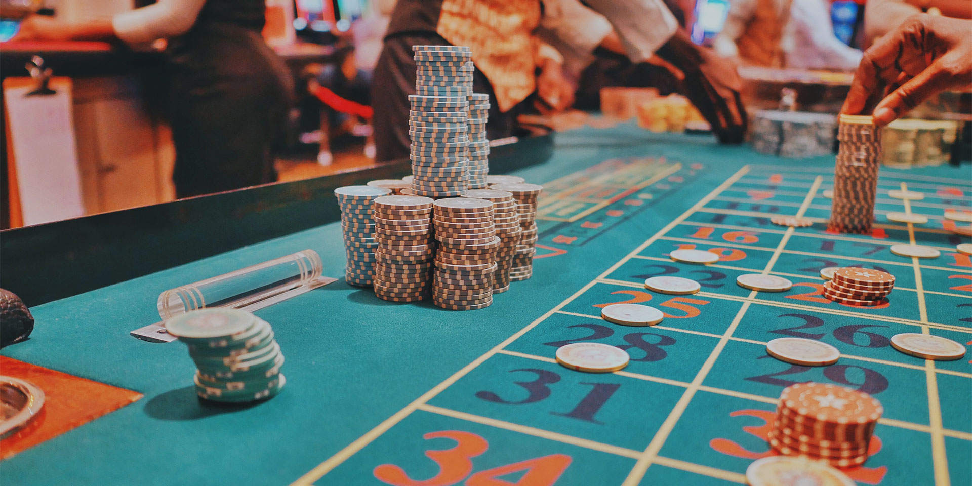 A bustling poker table decorated with red and green poker chips scattered around and stacked.