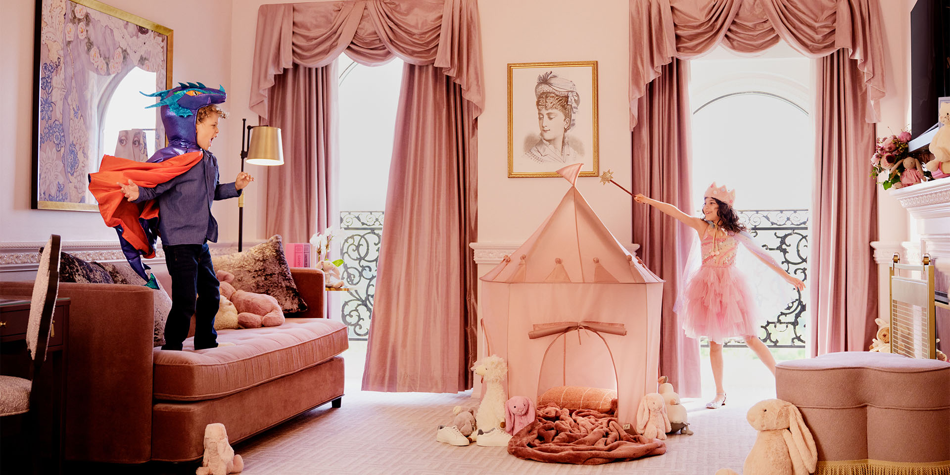 two kids playing dress up in a pink hotel room
