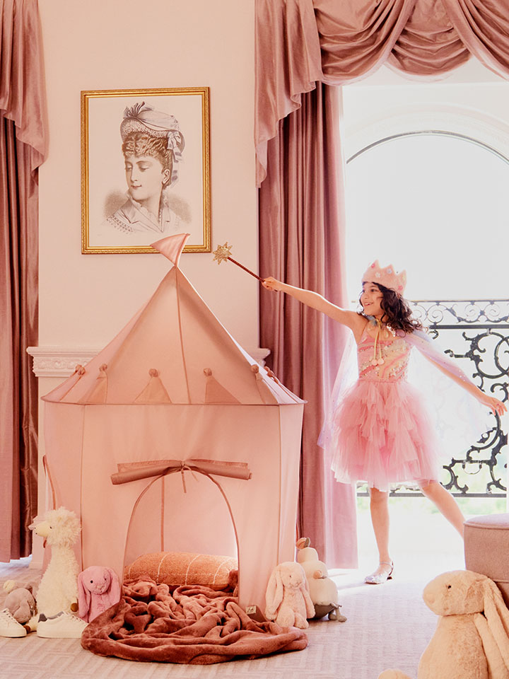 two kids playing dress up in a pink hotel room