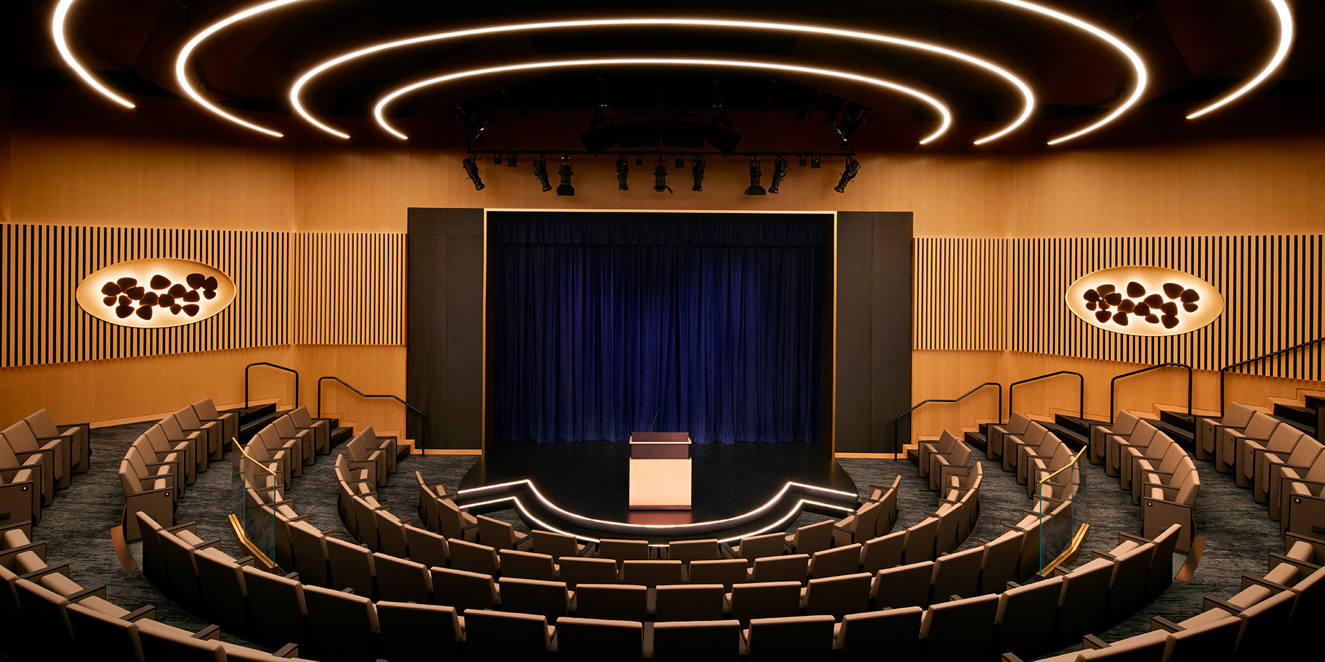 Large lecture hall boardroom with a bronze colored wall and dark blue curtain