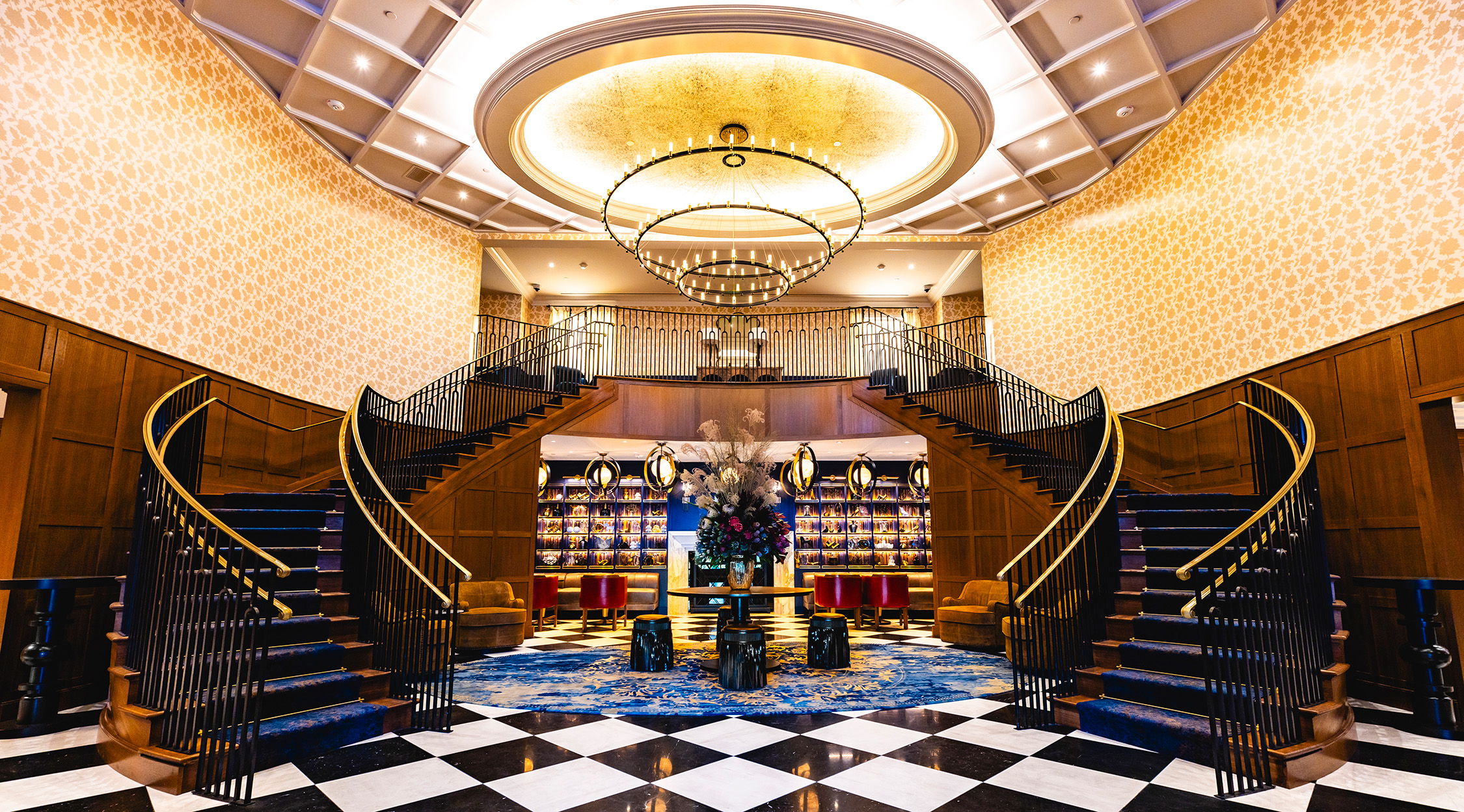 Lobby of The Grand Lodge at Nemacolin, with a split staircase, large chandelier, and fireplace