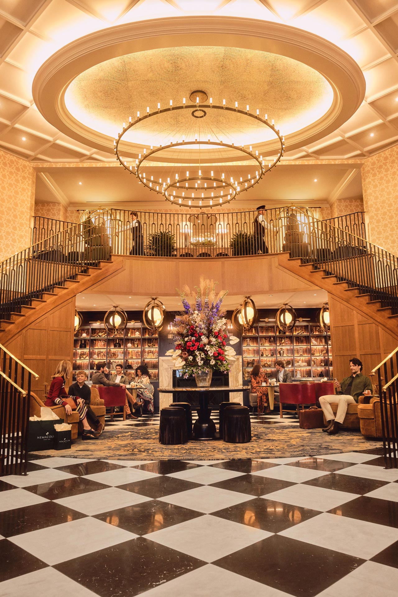 Click here to open the gallery overlay for the image: the grand lodge lobby with black and white floor and very large chandelier with stair cases on either side