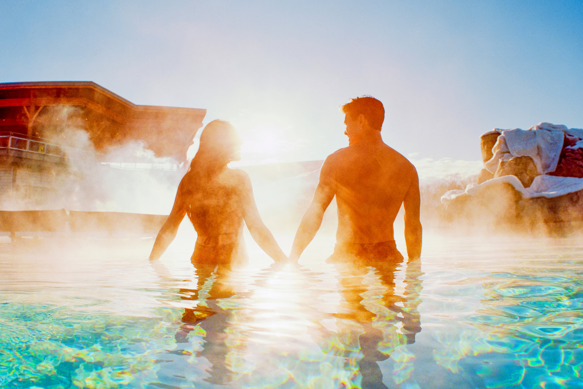 Click here to open the gallery overlay for the image: a man and woman holding hands in a steaming pool
