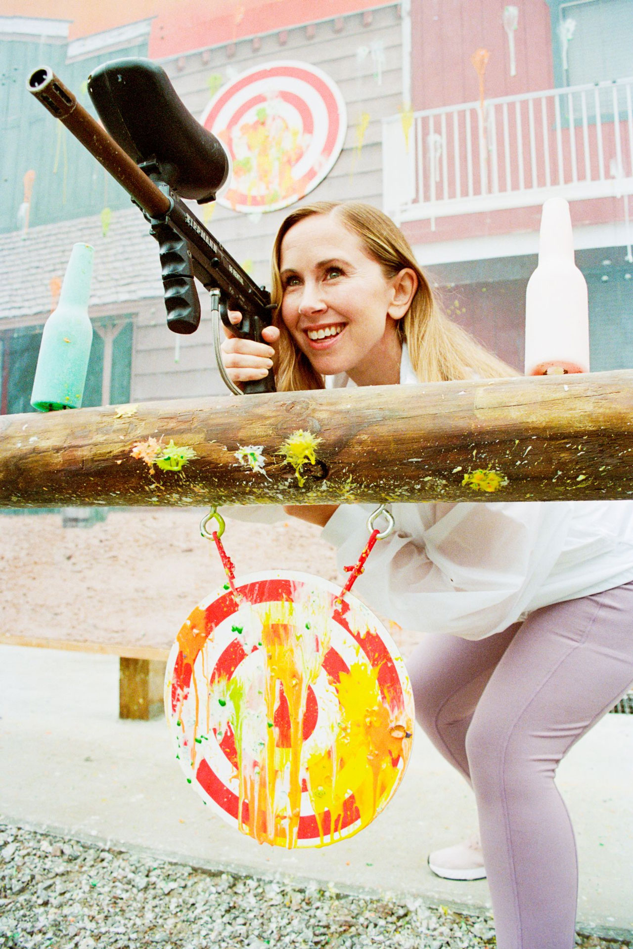 Click here to open the gallery overlay for the image: a woman smiling while playing paintball