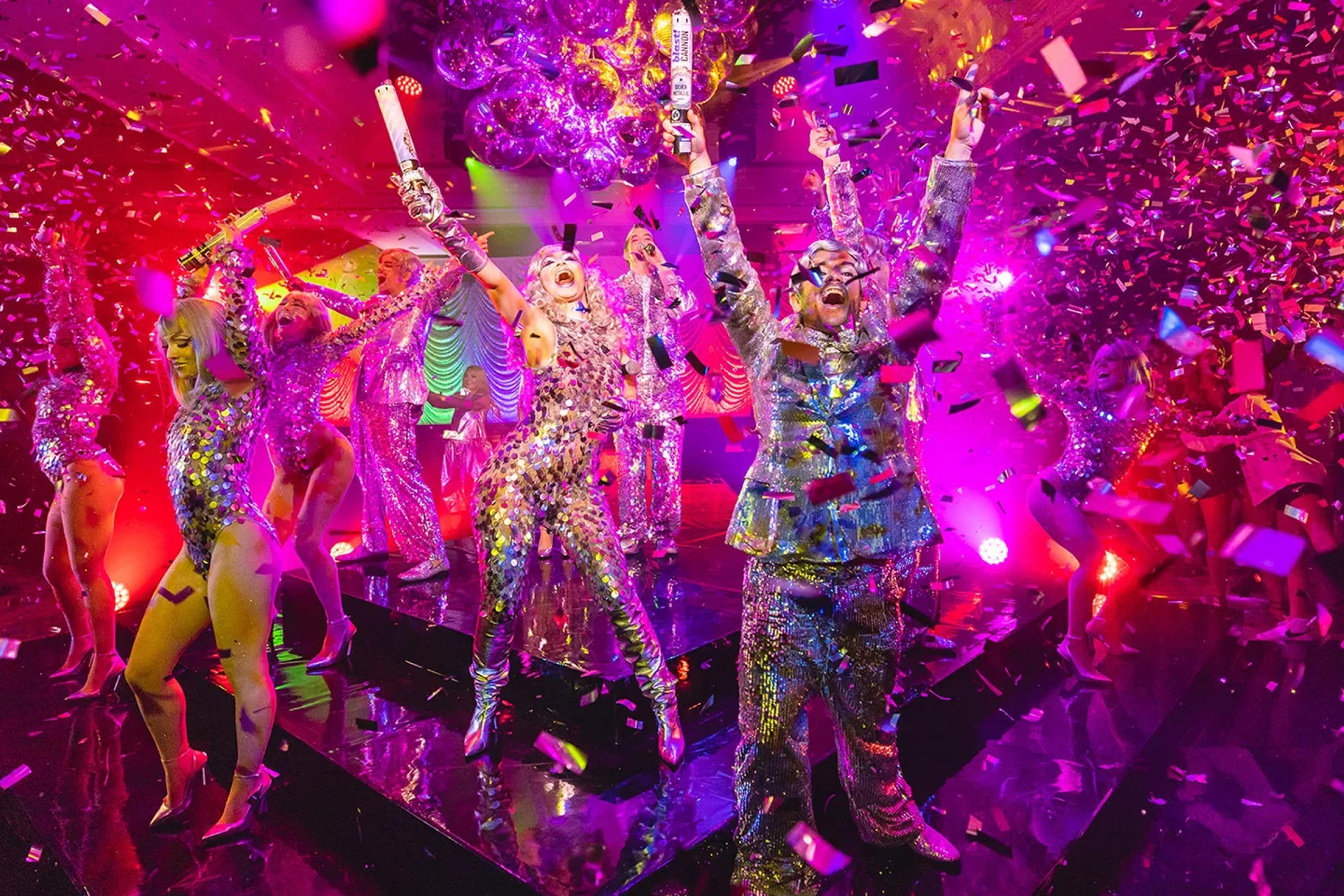Click here to open the gallery overlay for the image: people celebrating in a colorful setting with confetti