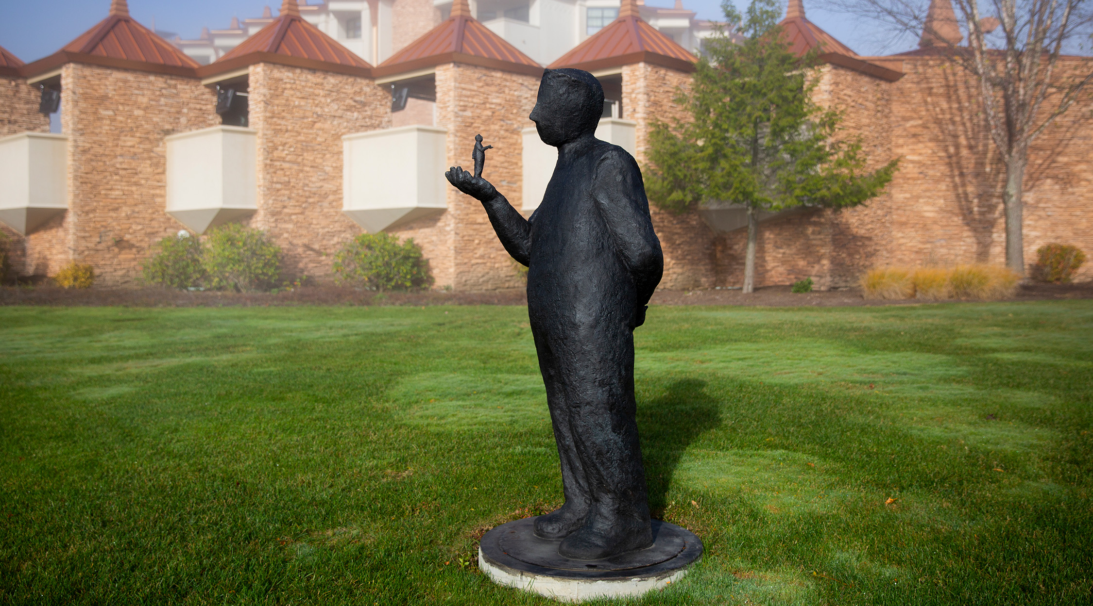 Outdoor sculpture of a man holding a smaller man in his hand on display outside the Falling Rock hotel at Nemacolin resort