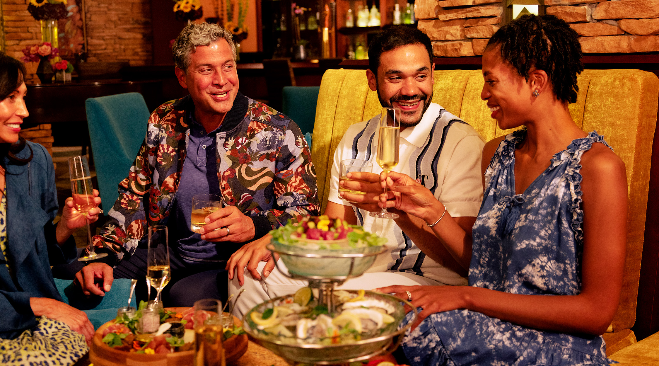 Two men and two women enjoying cocktails and a seafood tower at the casual Amber Bar restaurant at the Falling Rock hotel at Nemacolin resort