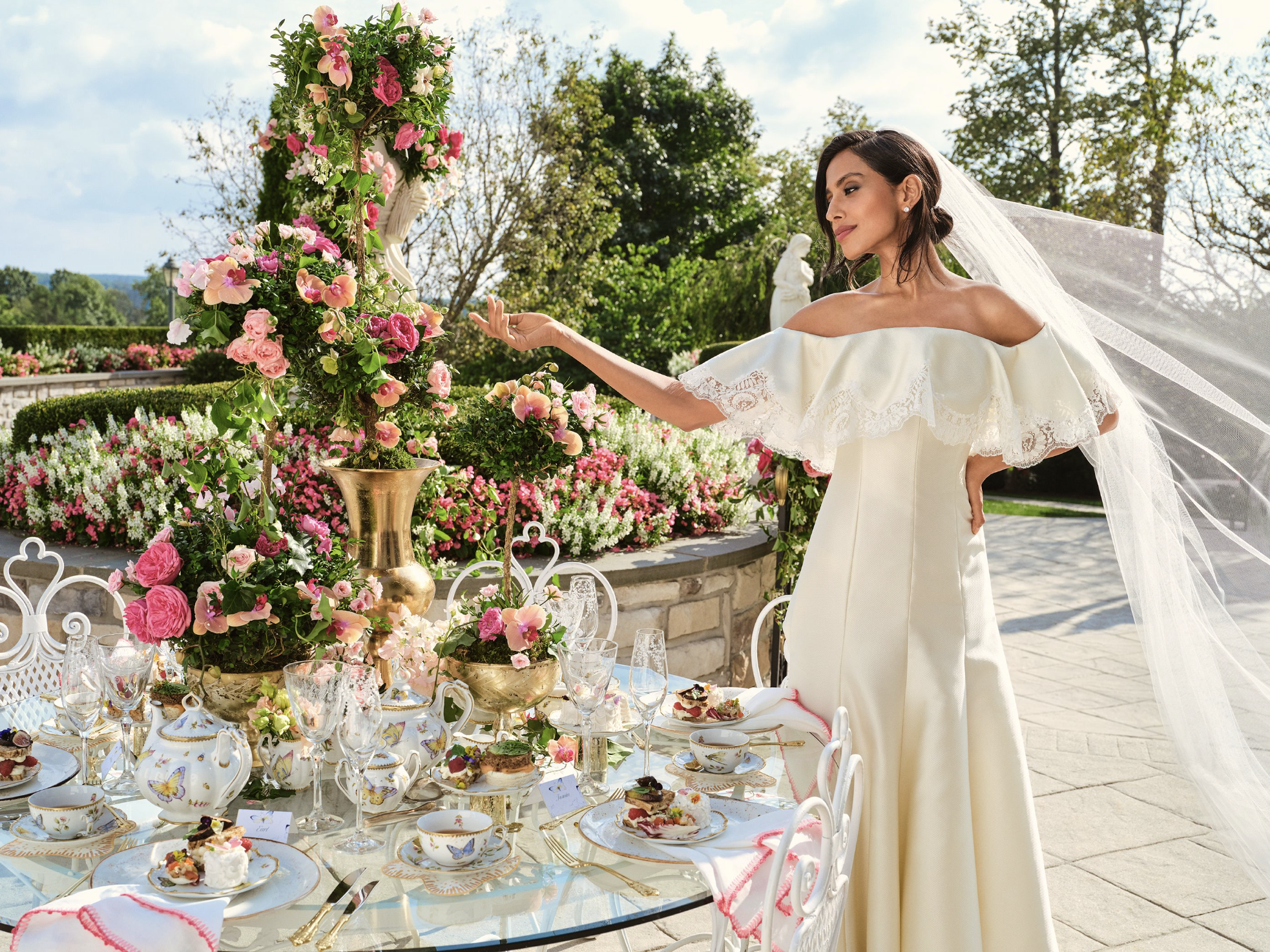 Girl stands in wedding dress and vail next to flowers