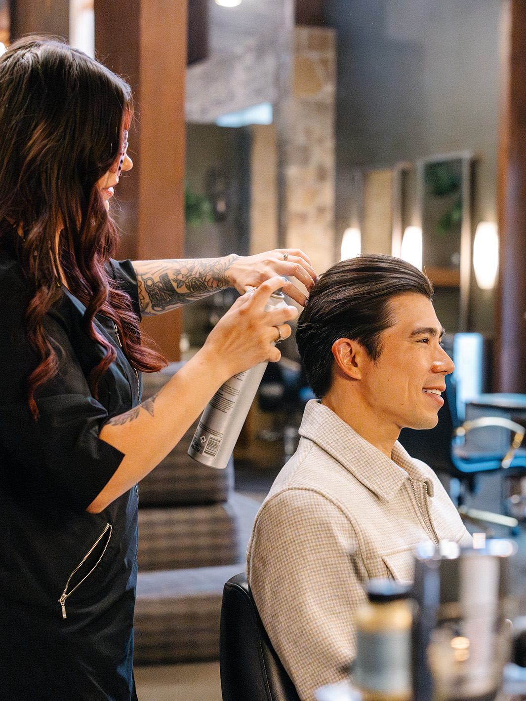 A man with brown hair having a hair service at a salon with a female stylist styling his hair