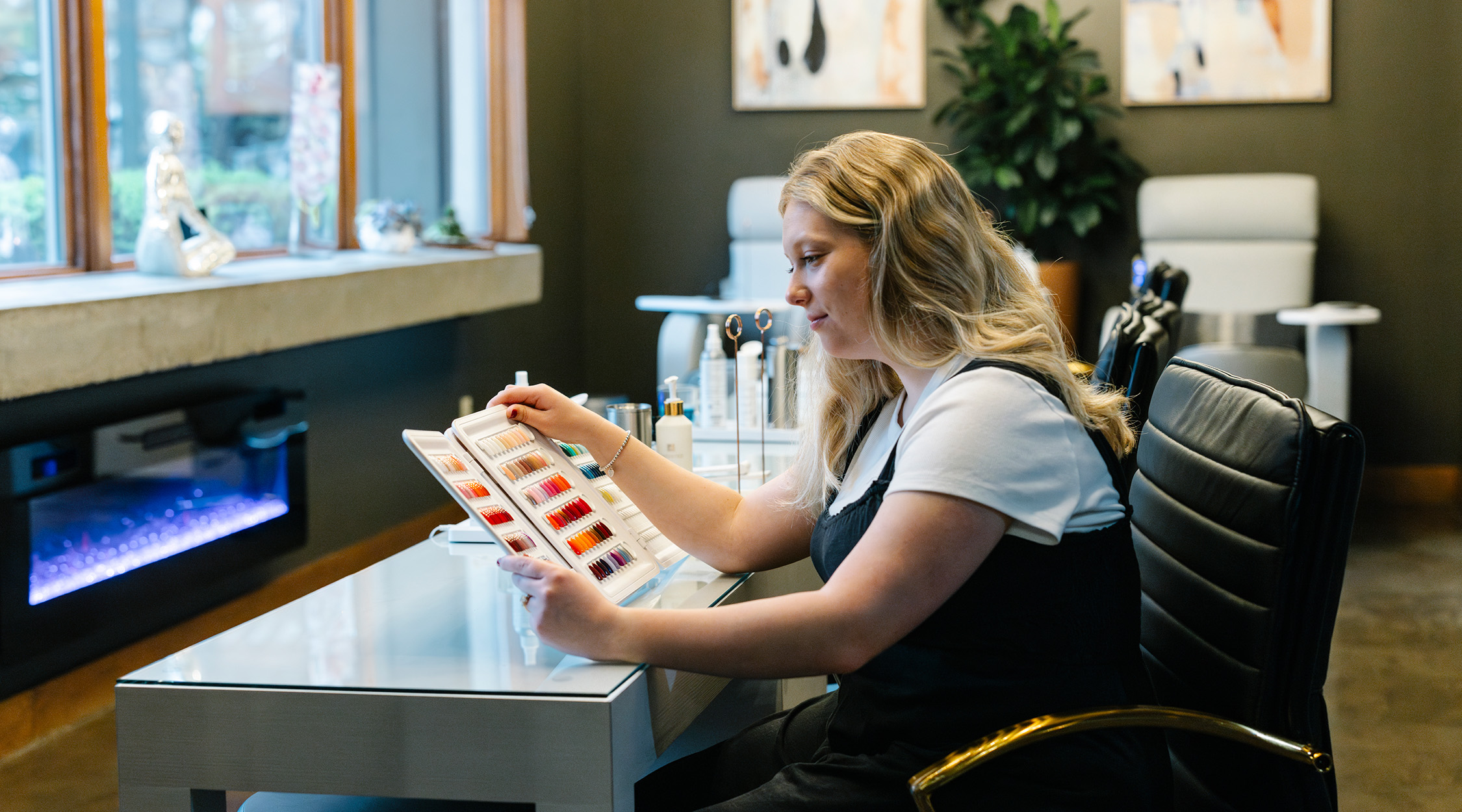 A woman with blond hair looking over a color card in a salon