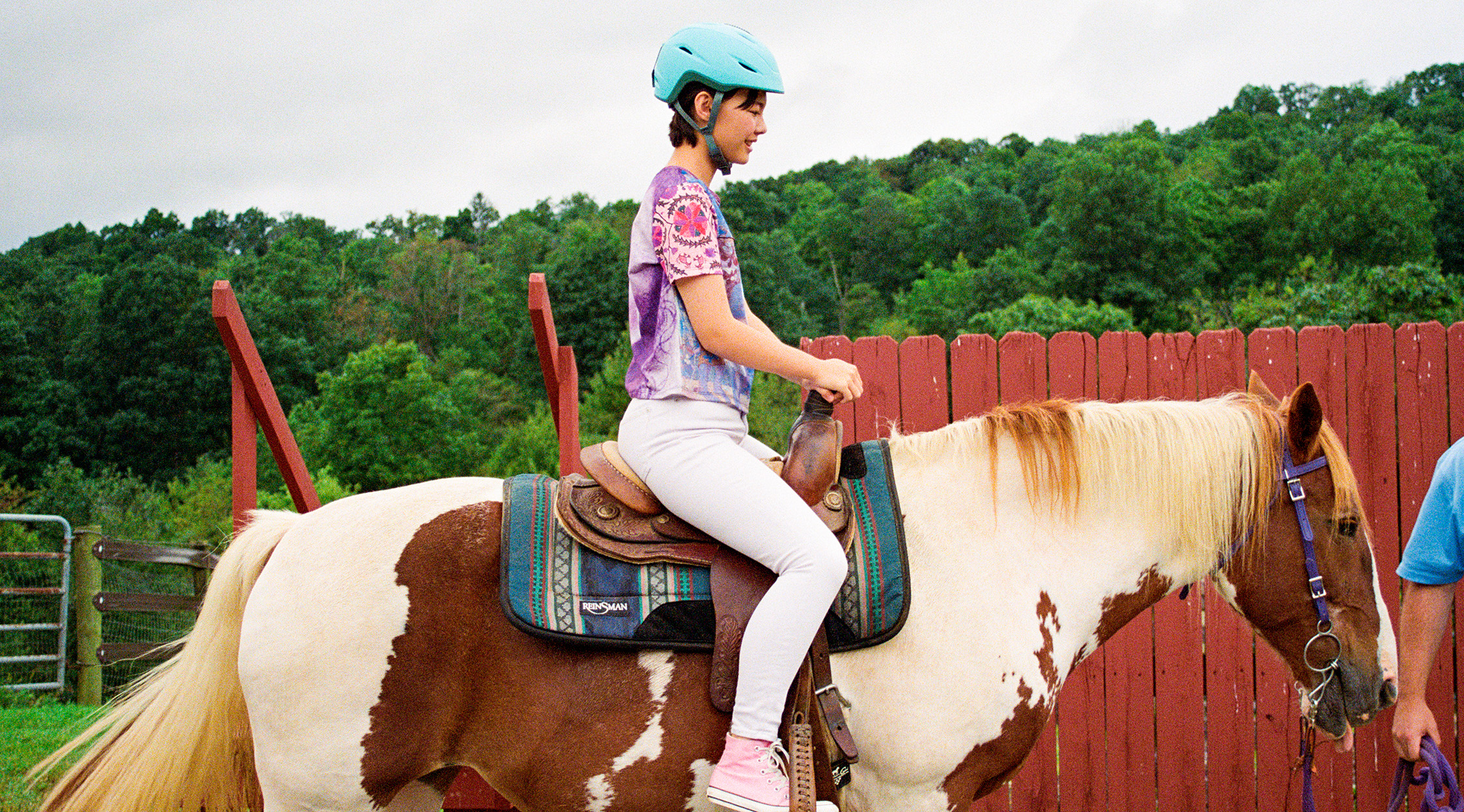 young woman wearing a helmet riding a brown and white horse