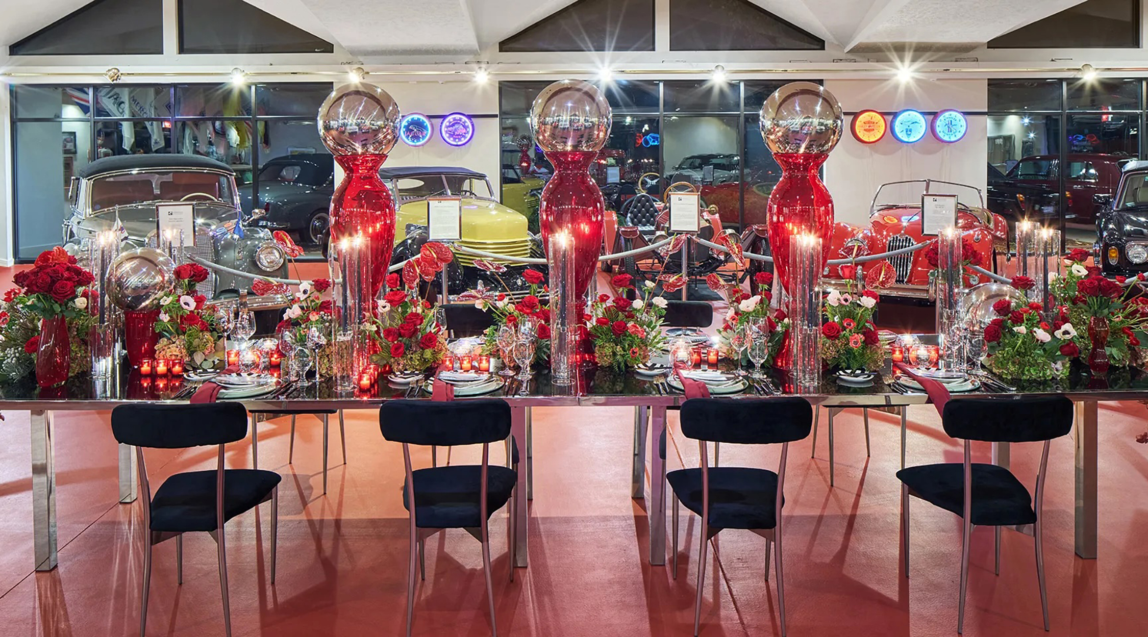 A tablescape of red, green, and black framed with antique cars at the Woodlands Auto Toy Store at Nemacolin resort.