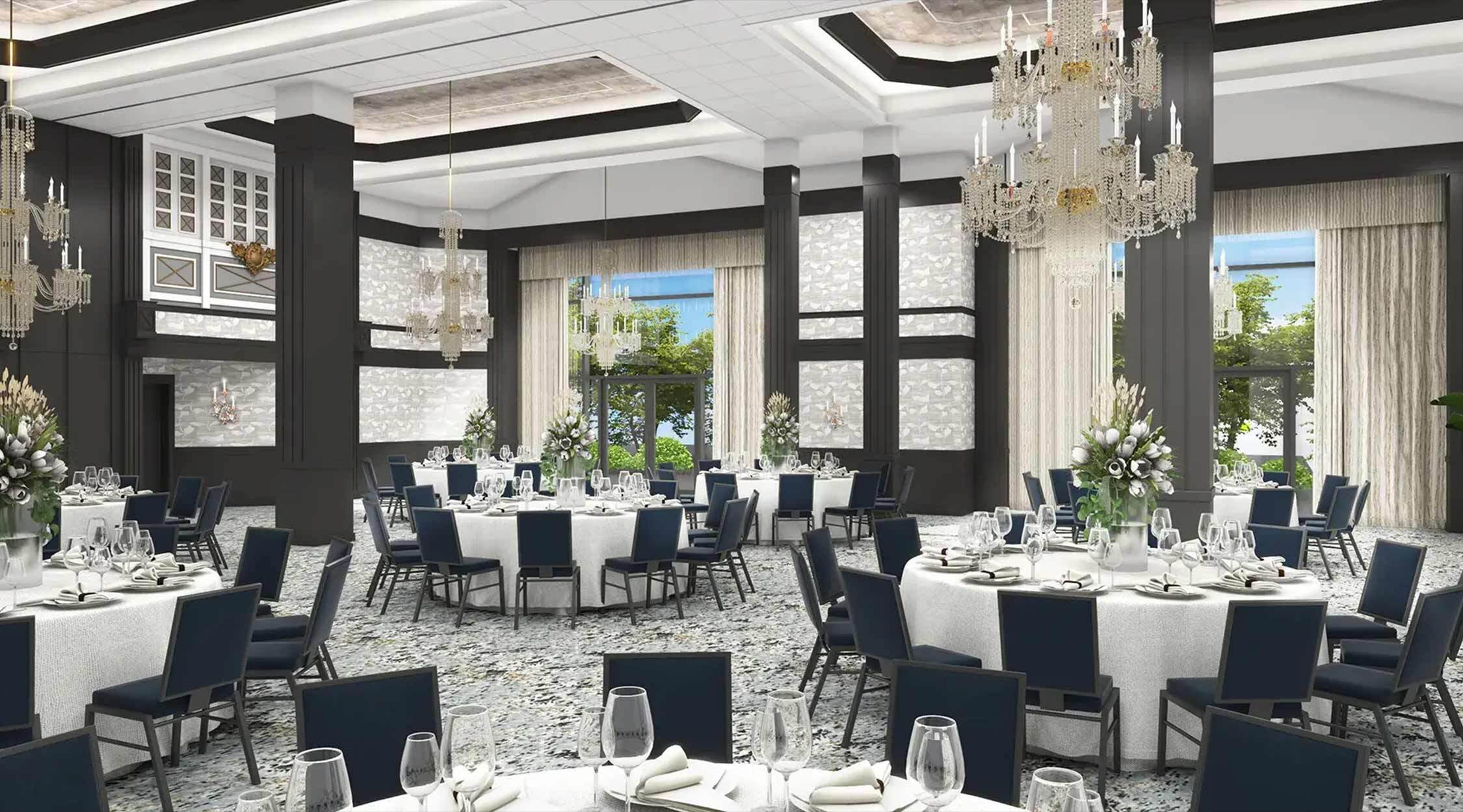 A ballroom with crystal chandeliers, deep-toned wood, light carpeting, and high ceilings decorated with white tablecloths, black chairs, and florals in the Grand Ballroom at Nemacolin resort