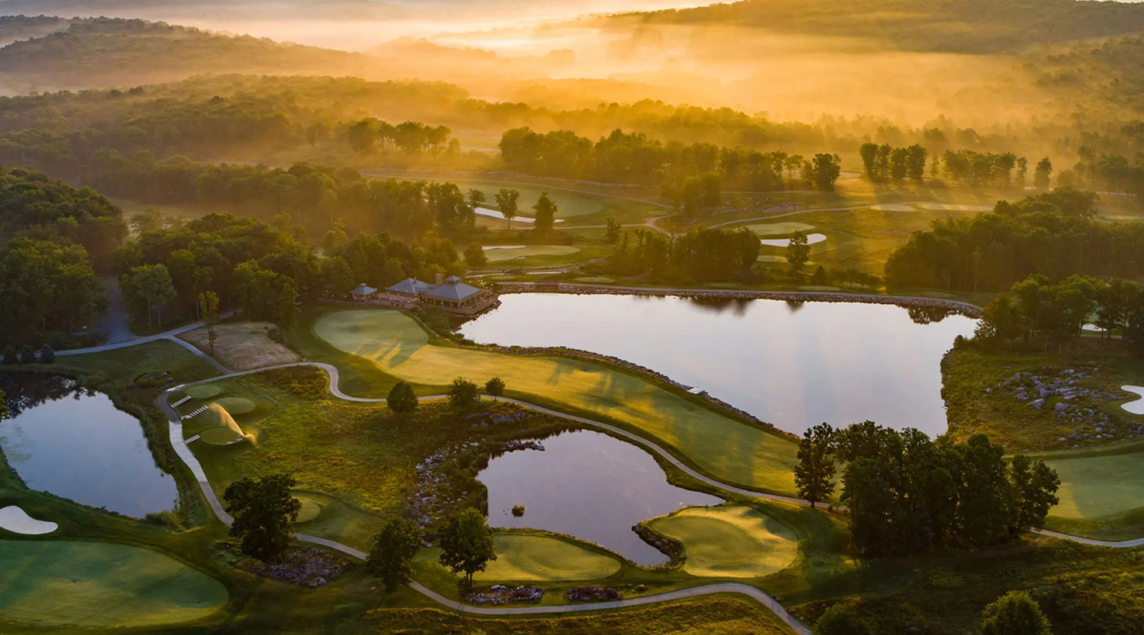 A foggy mountain sunrise showing the Mystic Rock Golf Course near the mid-way point and three ponds near Mulligans at Nemacolin resort