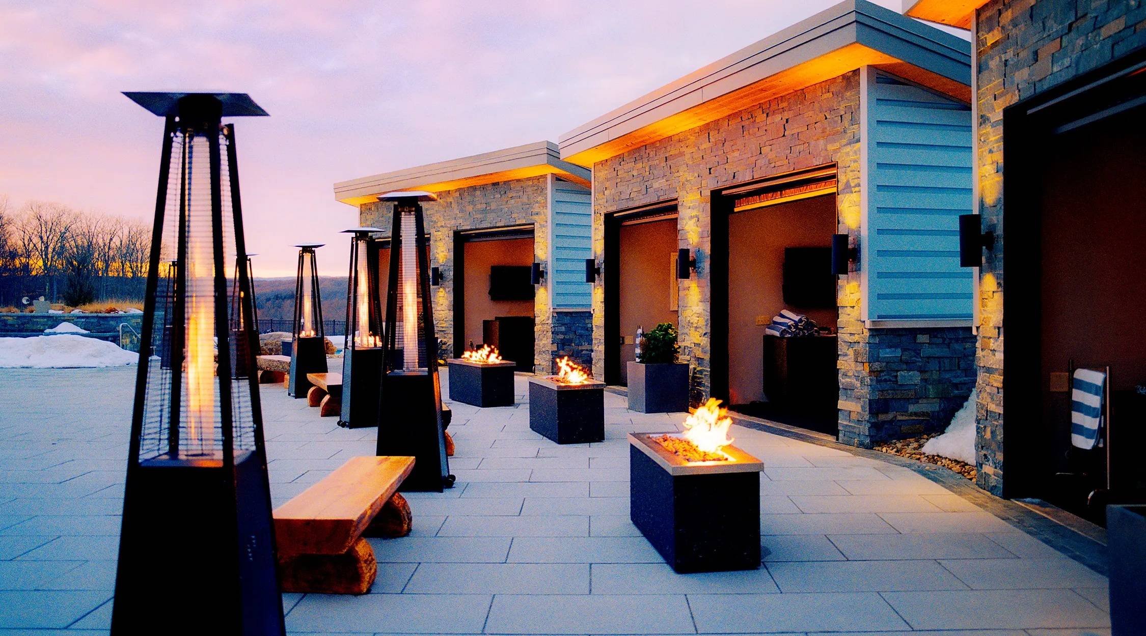 Cabanas at The Peak as dusk settles at Nemacolin. Fire pits and outdoor heaters are set in front of the cabanas.